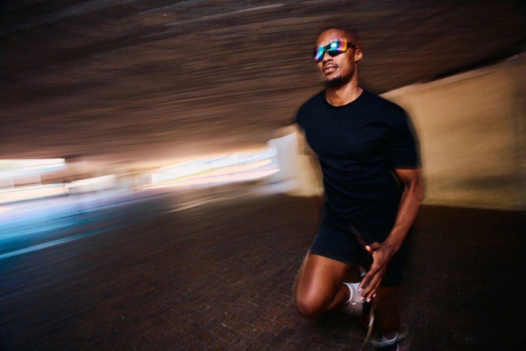 Male runner sprinting through underpass with motion blur, urban athlete running with speed during endurance training